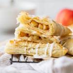 A stack of apple turnovers with one cut in half showing the apple filling.
