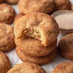 Three snickerdoodles stacked on top of each other. The top cookie has a bite missing.