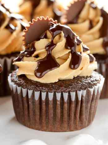 Close up of chocolate peanut butter cupcakes on a white cake stand.
