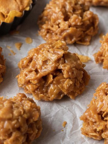 Several cornflake cookies on a piece of parchment paper.