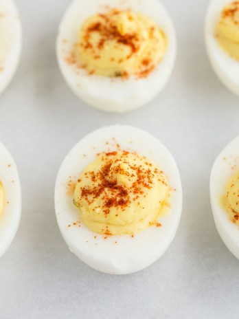 A close-up picture of deviled eggs on a piece of parchment paper.