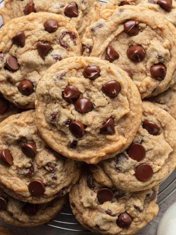 A pile of chocolate chip cookies in a round wire cooling rack.