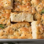 Several slices of focaccia bread in a metal baking pan.