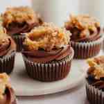 Several German Chocolate cupcakes on a marble serving plate.