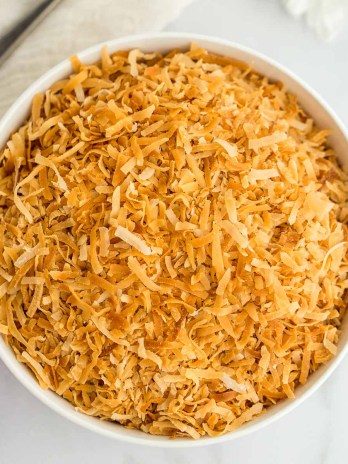 A white bowl filled with toasted coconut.