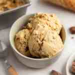 A bowl filled with three scoops of peanut butter ice cream.