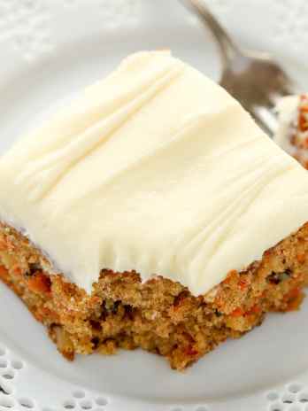A slice of pineapple carrot cake on a white plate with a fork.
