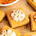 Several pumpkin cheesecake bars on a piece of brown parchment paper.