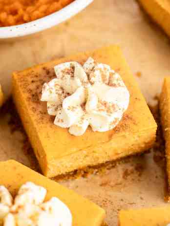 Several pumpkin cheesecake bars on a piece of brown parchment paper.