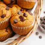 Several pumpkin chocolate chip muffins in a basket.