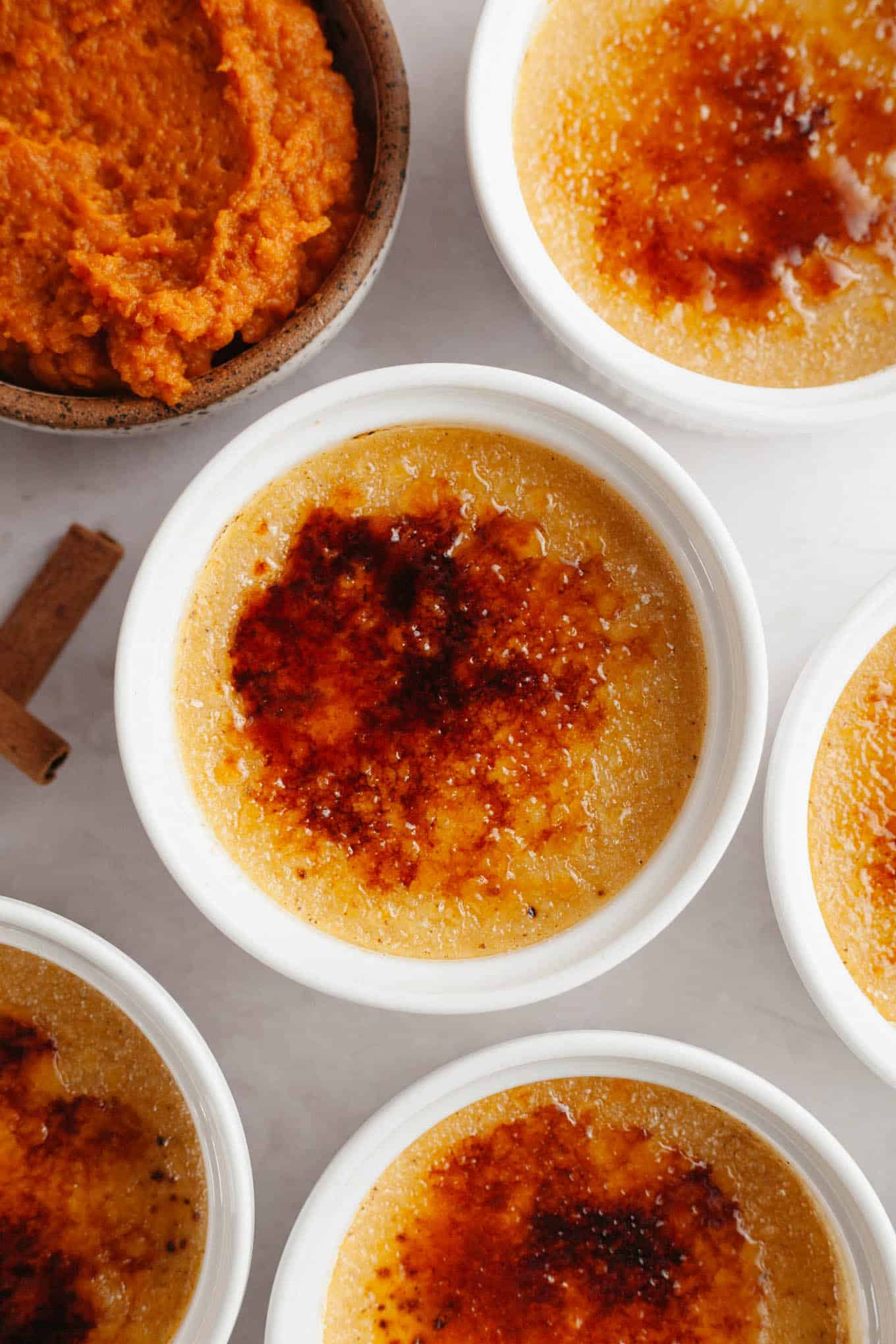 An overhead view of pumpkin crème brûlée in individual ramekins. 