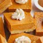Several pumpkin pie bars topped with whipped cream.