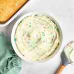 A white bowl filled with rainbow chip frosting.