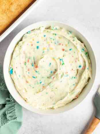 A white bowl filled with rainbow chip frosting.