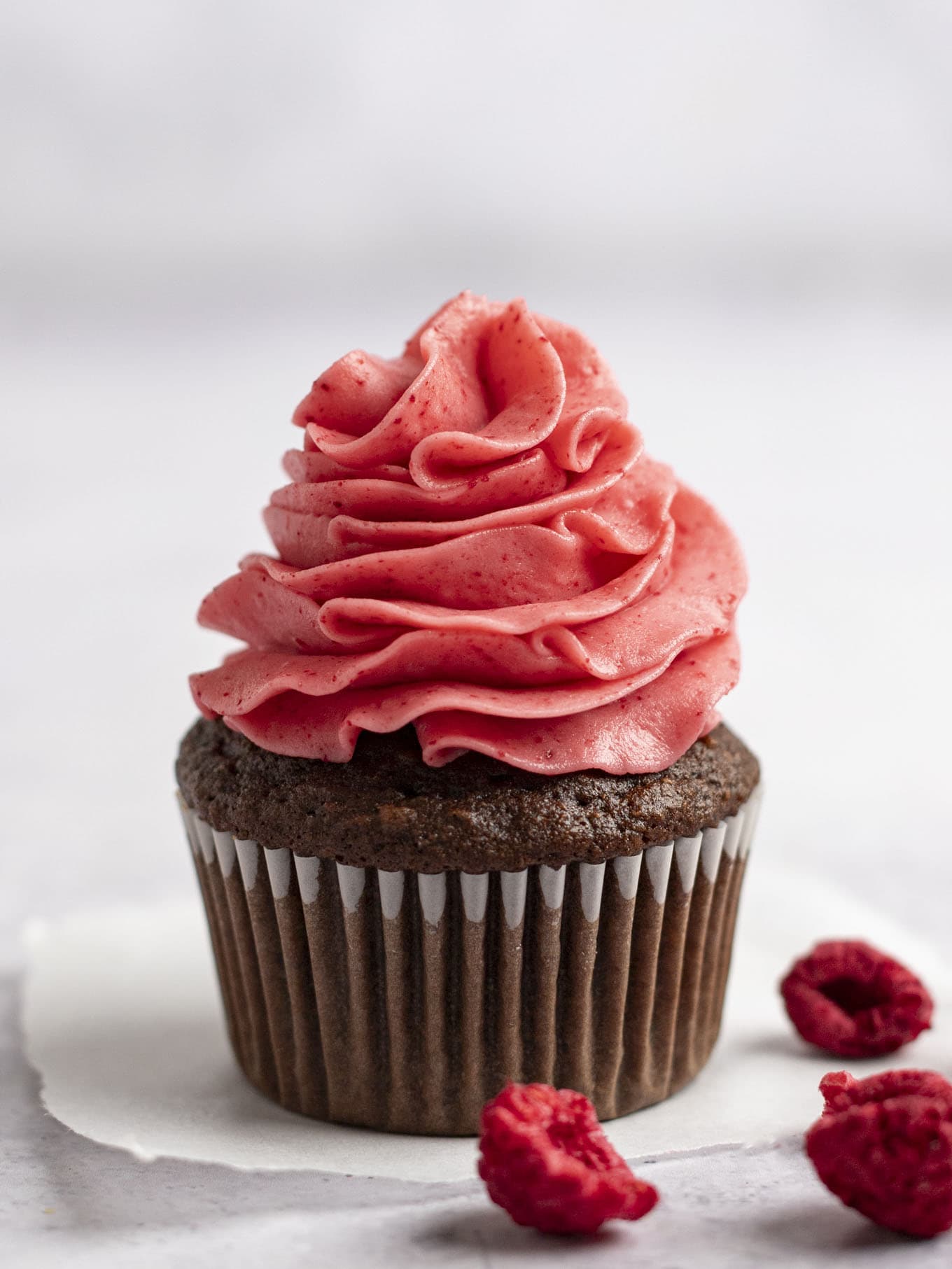 A chocolate cupcake topped with raspberry frosting. 