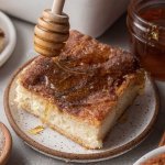 A slice of sopapilla cheesecake being drizzled with honey.