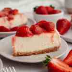 A slice of strawberry cheesecake on a white plate.