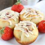 Three strawberry cinnamon rolls on a white plate.
